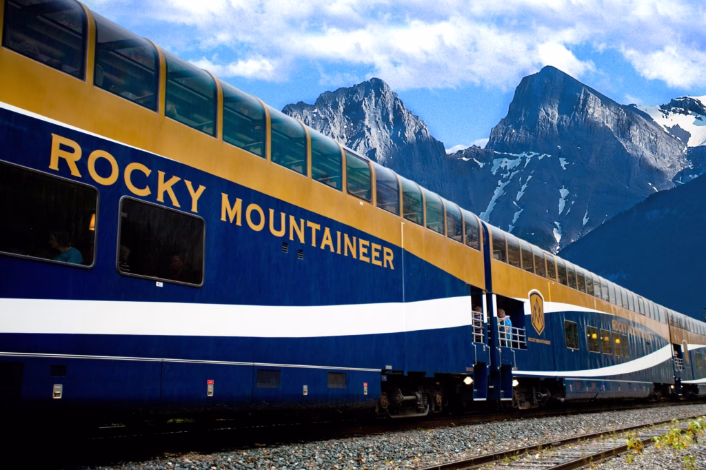 Rocky Mountaineer luxury train gliding along tracks with scenic mountain backdrop